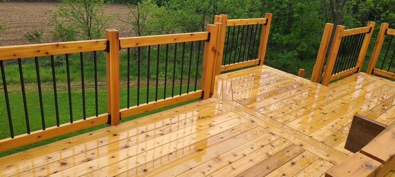 New wooden deck with metal railings overlooking green landscape and trees