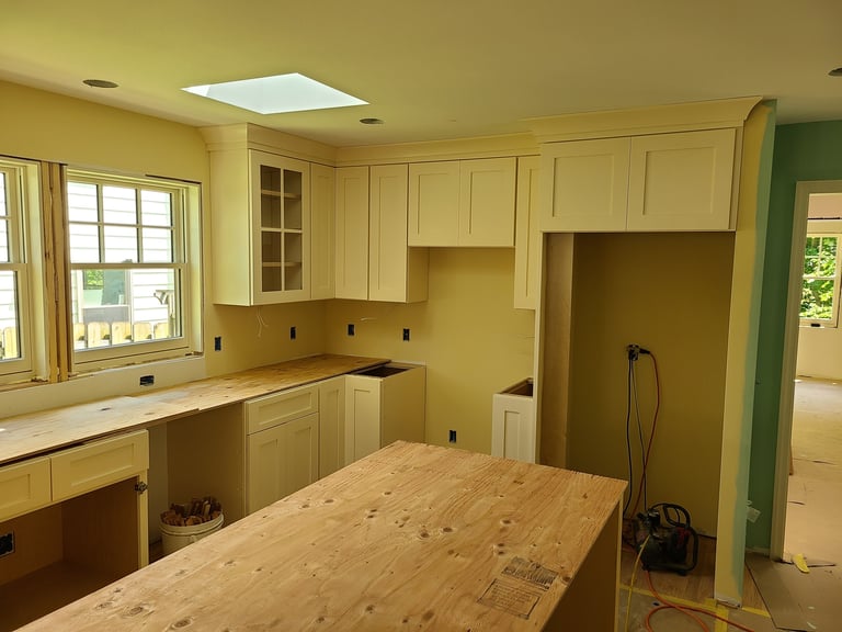 Empty kitchen under renovation with yellow cabinets, wooden island countertop, and open framing to adjacent rooms