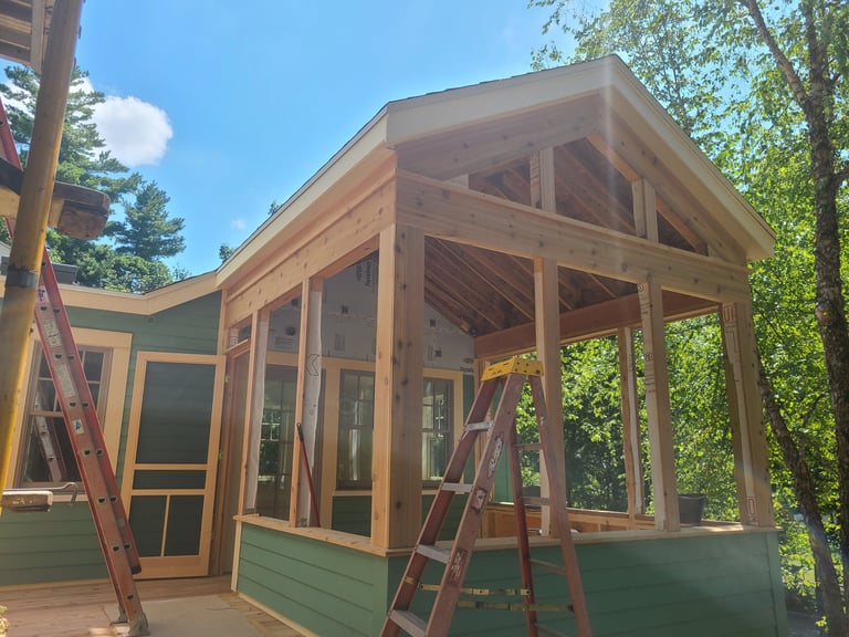 Wooden cabin with large windows under construction surrounded by trees on a sunny day